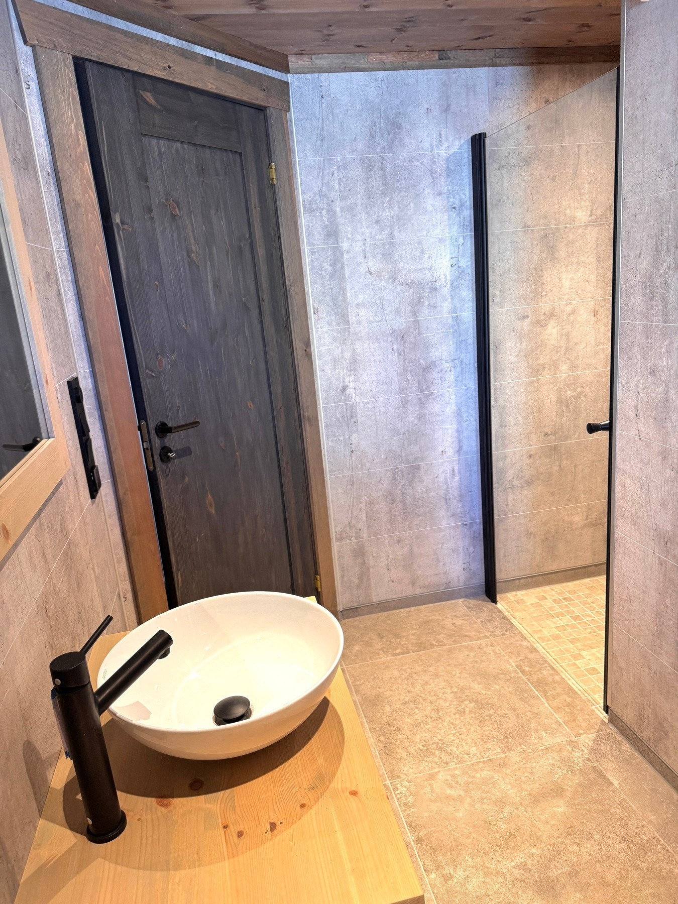 Rommet er innredet med baderomsinnredning med servant, veggmontert toalett og dusjvegger Galleribilde