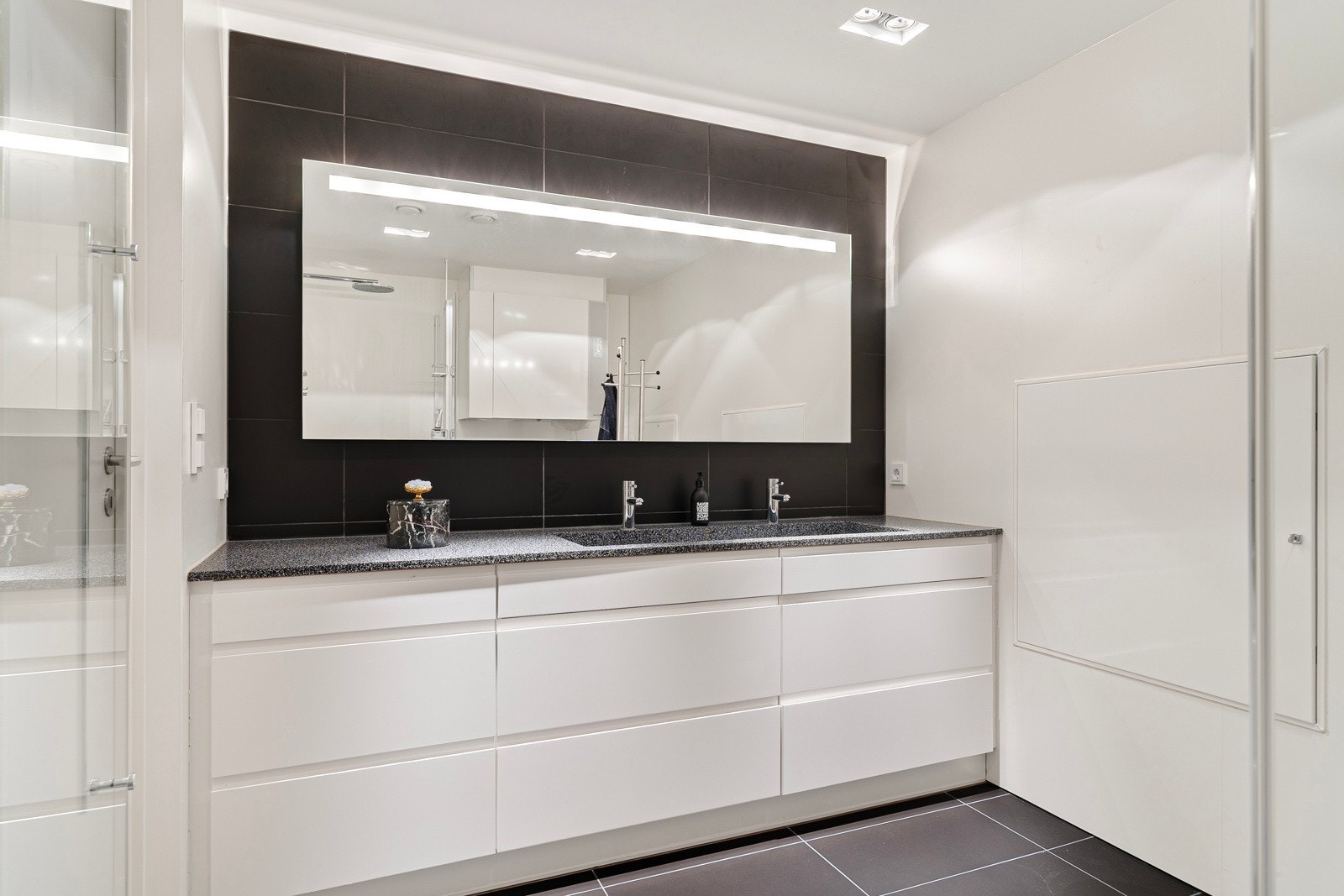 Velutstyrt med dusjhjørne med innfellbare glassdører, servant og opplegg for vaskemaskin. Galleribilde