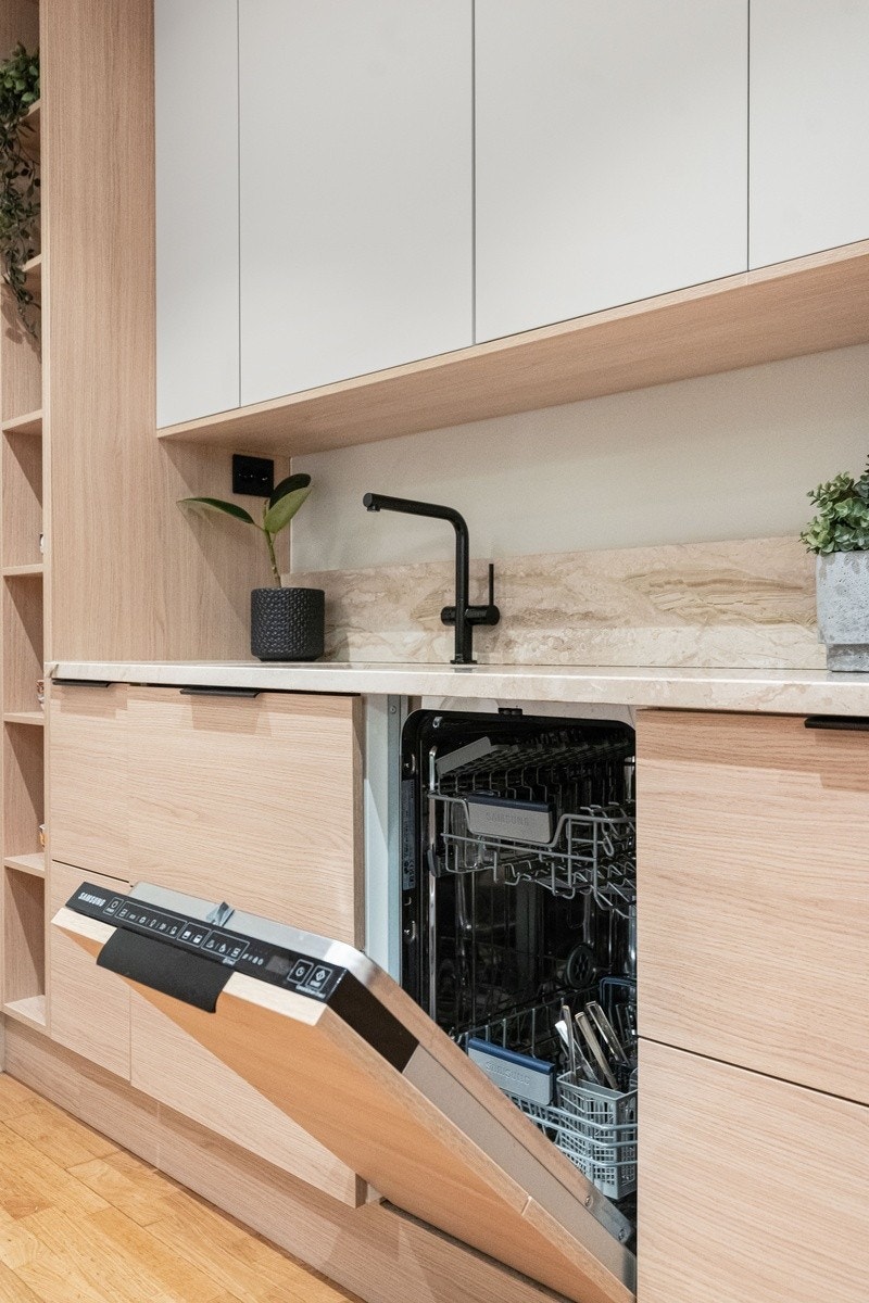 Kompakt og funksjonelt kjøkken med integrerte hvitevarer. Hvite fronter og marmor-benkeplate gir et stilrent uttrykk. Galleribilde