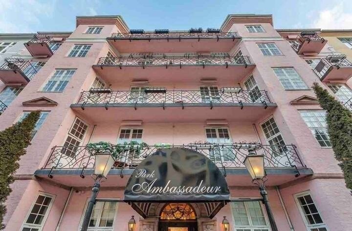 Bilde av bygget fra utsiden, som viser en klassisk bygård med velholdt fasade og grøntområde foran. Galleribilde