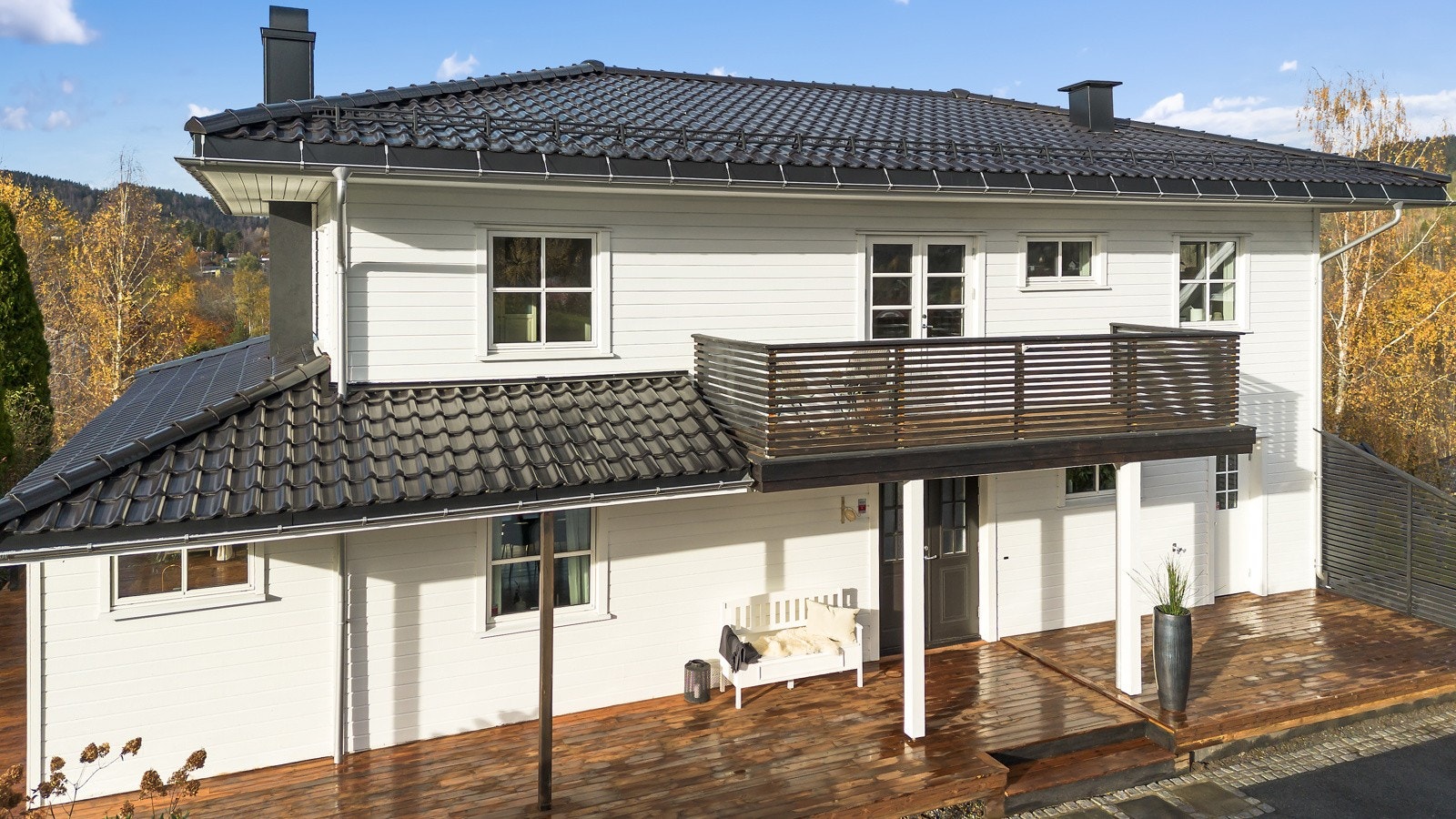 Det er store terrasser på alle sider av huset, her fra inngangssiden mot gårdsplassen med fin sydøstvendt terrasse med morgen- og formiddagssol Galleribilde