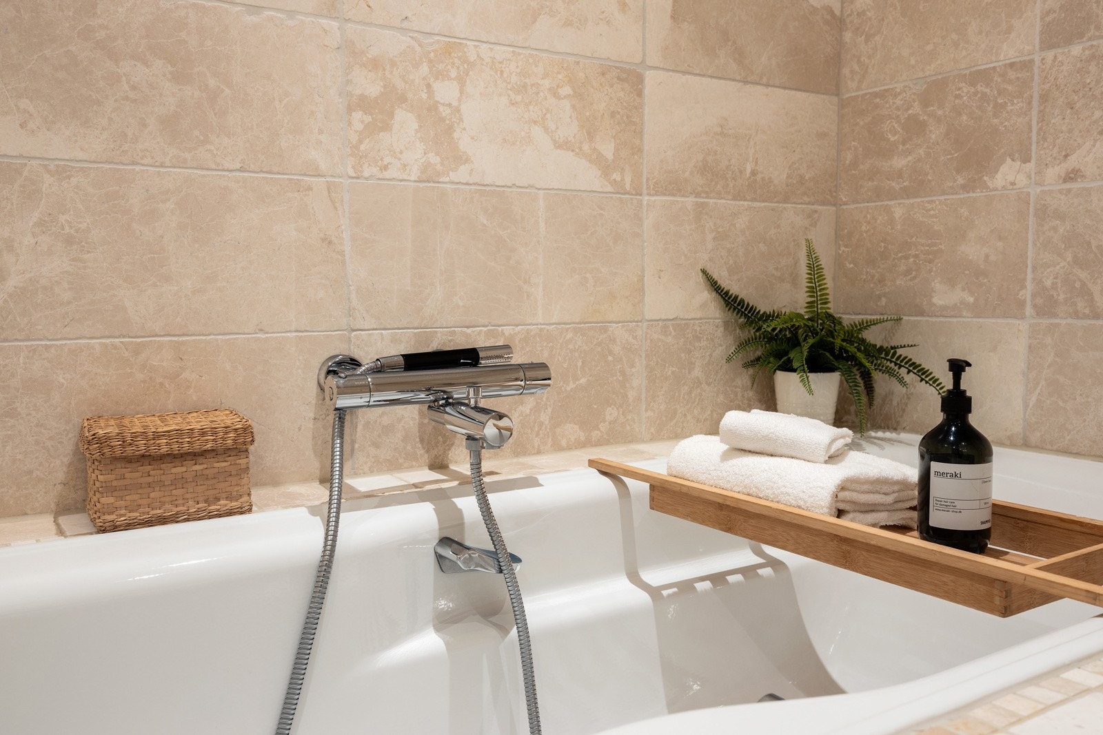 Rommet er innredet med åpent dusjhjørne med innbygningsarmatur, innmurt badekar, servantskap med servant og speil over servanten og sideskap samt innbygget, vegghengt toalett. Galleribilde