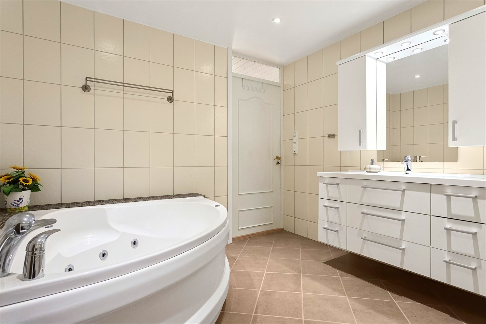 Stort flislagt bad på 11 kvm med veggmontert wc, hjørne boblekar, servant, uttak for vaskemaskin m.m. Galleribilde