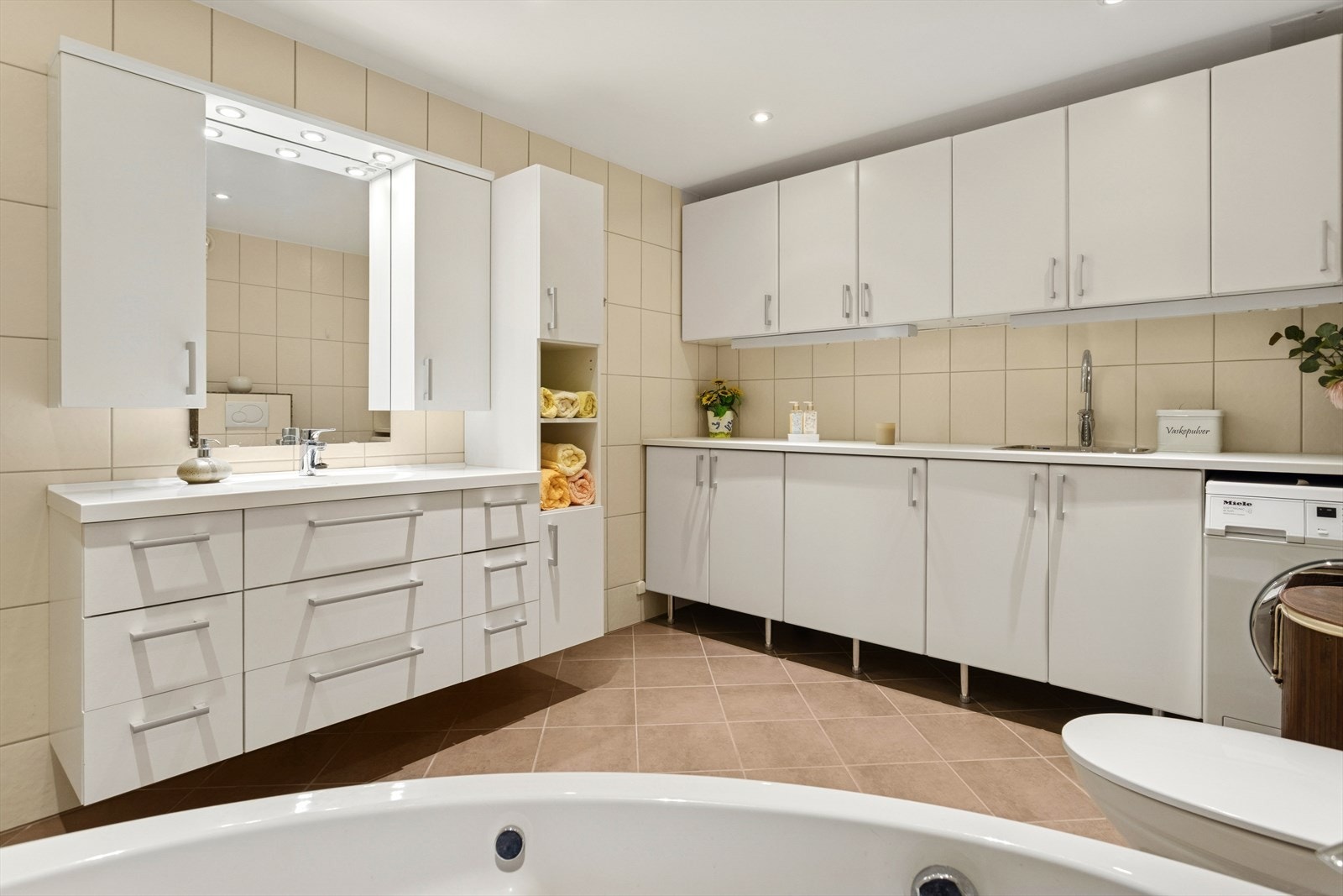 Stort flislagt bad fra 2011 på 11 kvm med veggmontert wc, hjørne boblekar, servant, uttak for vaskemaskin m.m. Galleribilde