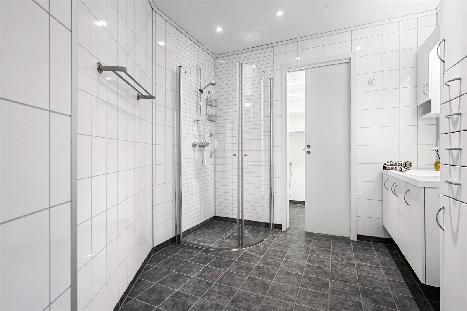 Pent bad som er innredet med vegghengt toalett, innredning med servant og dusjdører. Fra badet er det skyvedør inn til vaskerommet. Galleribilde