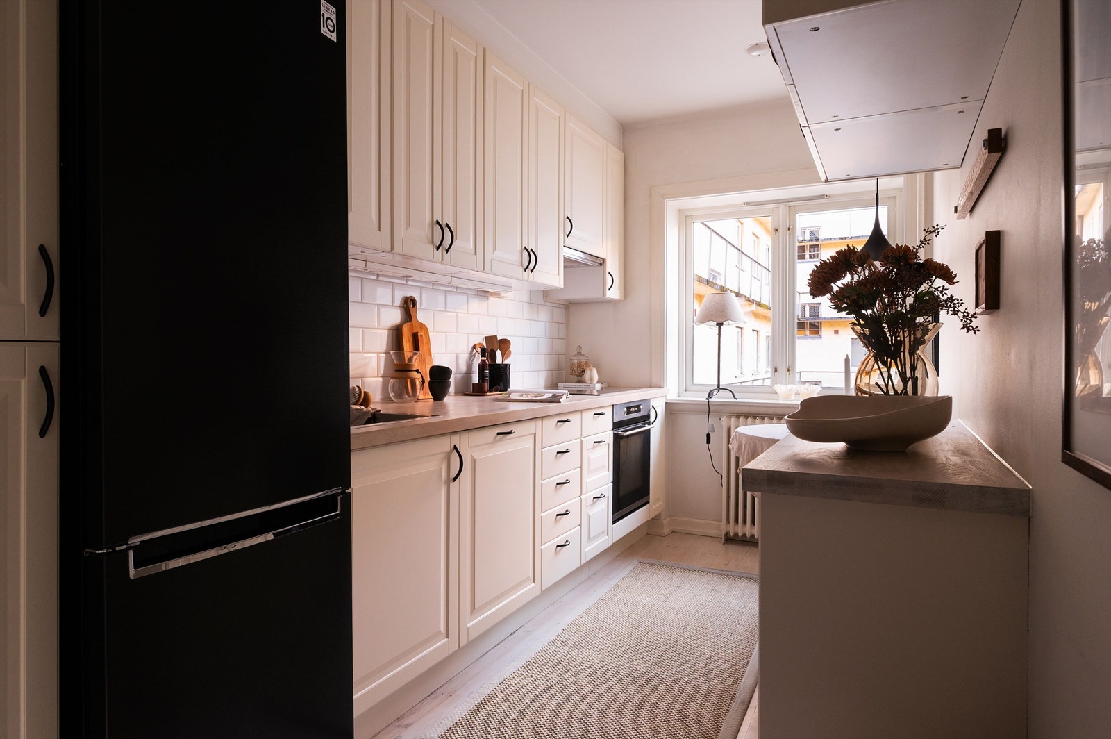 Kjøkkeninnredning med profilerte fronter, utstyrt med integrert stekeovn og platetopp. Galleribilde