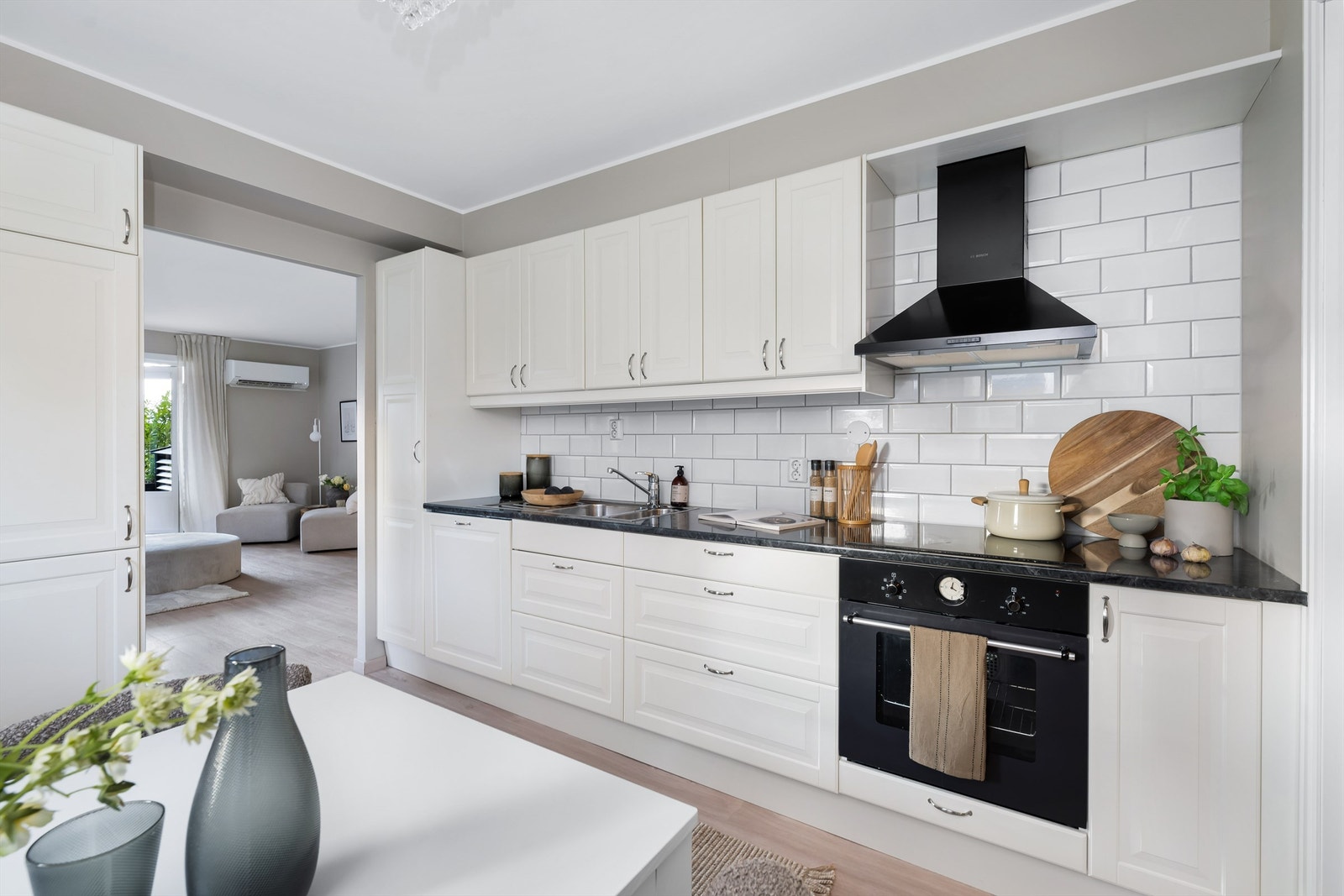 Pent og innholdsrikt kjøkken fra Ikea med profilerte fronter og laminat benkeplate. Hvite fliser på vegg over benk. Galleribilde