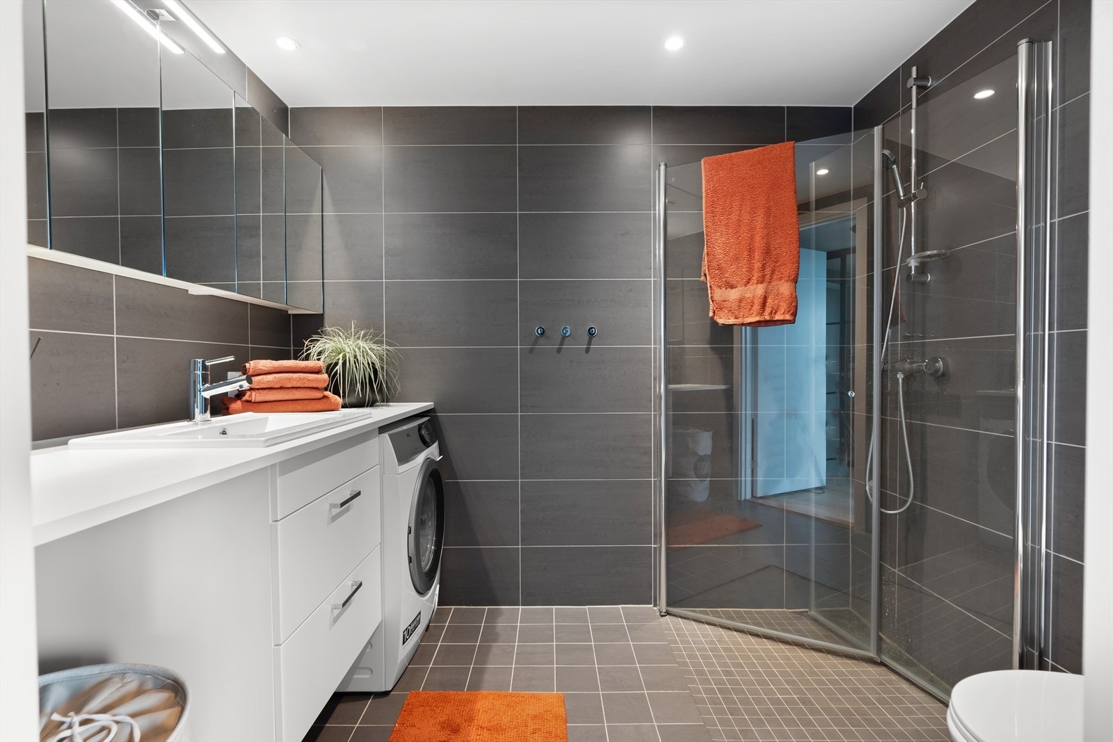 Badet er innredet med lys innredning med servant og ettgreps blandebatteri, vegghengt toalett og dusjhjørne med inn-utadslående dusjvegger. Det er Downlights med dimmer på bad som gir godt med lys og kan justeres etter behov. Galleribilde