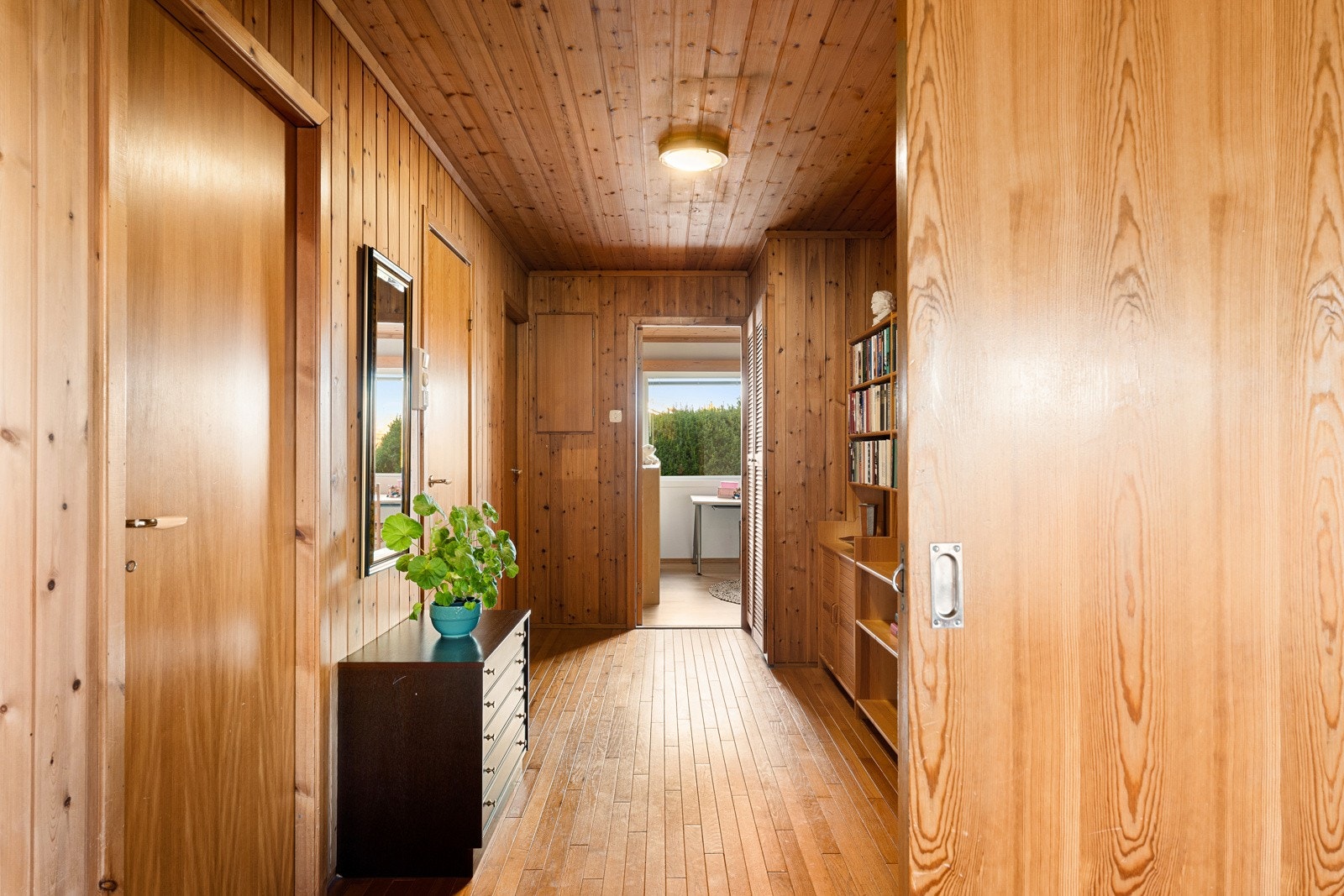 Den innredede bibliotek og arbeidsplassen i gangen gir både funksjon og særpreg, og understreker boligens fleksible planløsning. Galleribilde