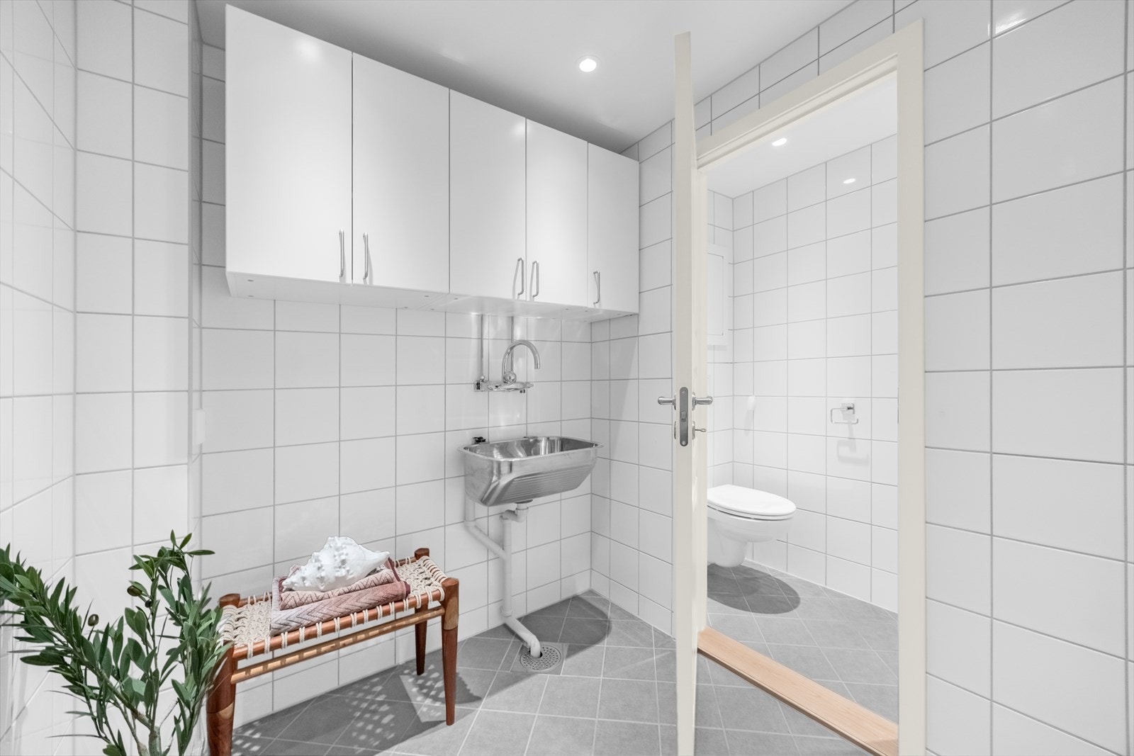 Praktisk vaskerom innredet med overskap, vegghengt skyllekum og veggmontert ett-greps blandebatteri. Galleribilde