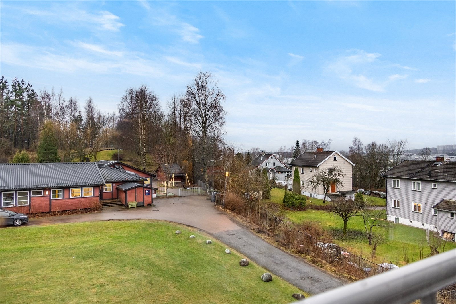 Utsikten fra balkongen viser et trivelig nabolag med grøntområder og nærliggende boligbebyggelse. Galleribilde