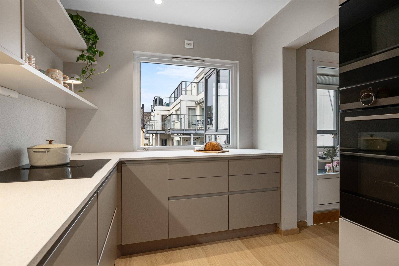 Det store kjøkkenvinduet slipper inn rikelig med naturlig lys og gir et hyggelig utsyn som gjør matlagingen til en ekstra trivelig opplevelse. Innredningen har både under- og overskap, i tillegg til åpne hyller som gir gode oppbevaringsmuligheter Galleribilde