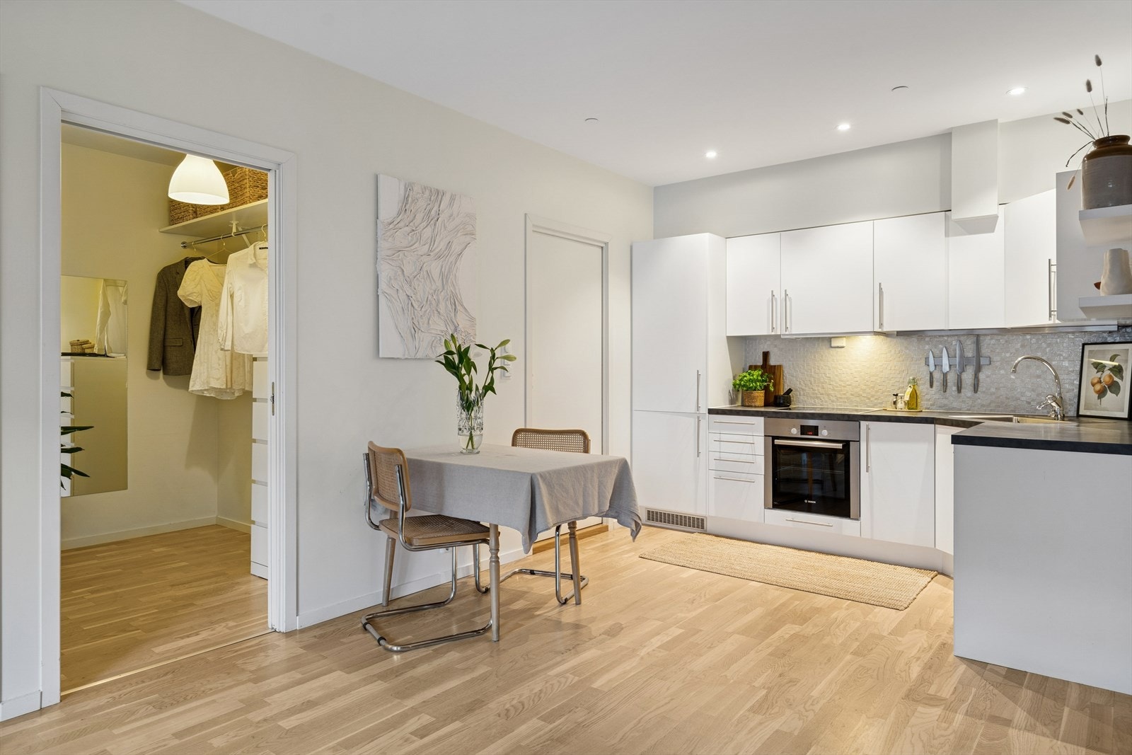 Pent kjøkken med slette fronter og fliser på vegg over benk. Galleribilde