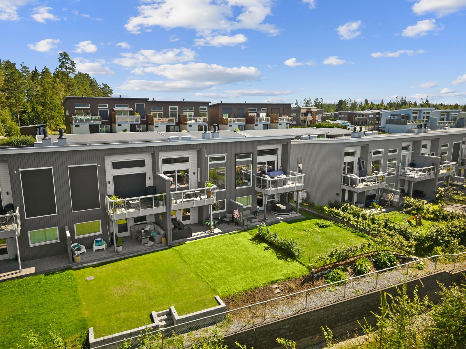 Oversiktsbilde av rekkehusbebyggelsen på Pepperstad. Caspar Wessels vei 32 ligger skjermet til med private uteplasser, gode solforhold og grønt fellesareal rett utenfor boligen. Galleribilde