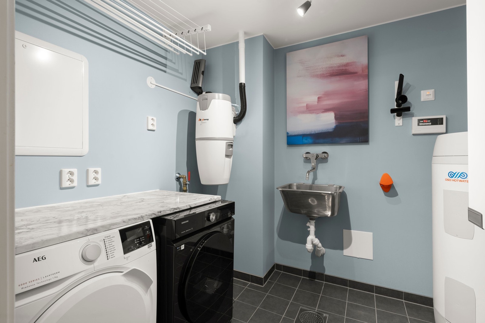 Praktisk teknisk rom med opplegg for vaskemaskin, tørketrommel og skyllekar, samt plass til boligens tekniske installasjoner. Et funksjonelt rom som gir god oversikt og orden i hverdagen. Galleribilde