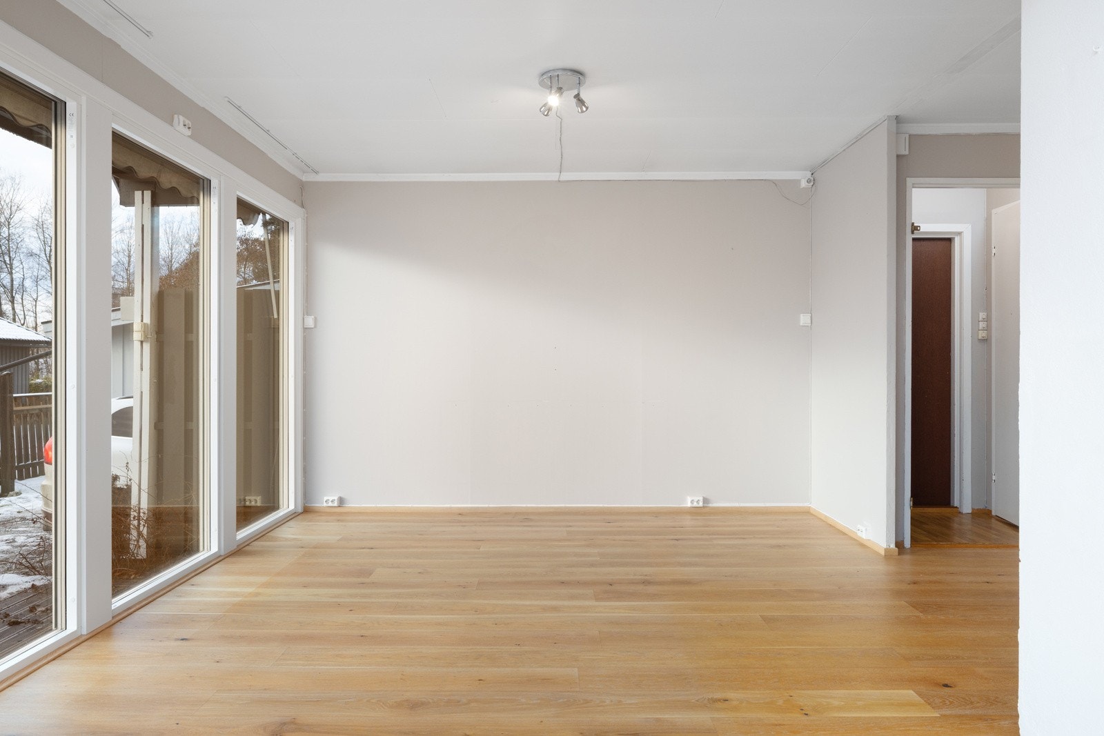 Lyst og romslig oppholdsrom med store vindusflater, enkel møblering og god forbindelse til uteområdet. Galleribilde