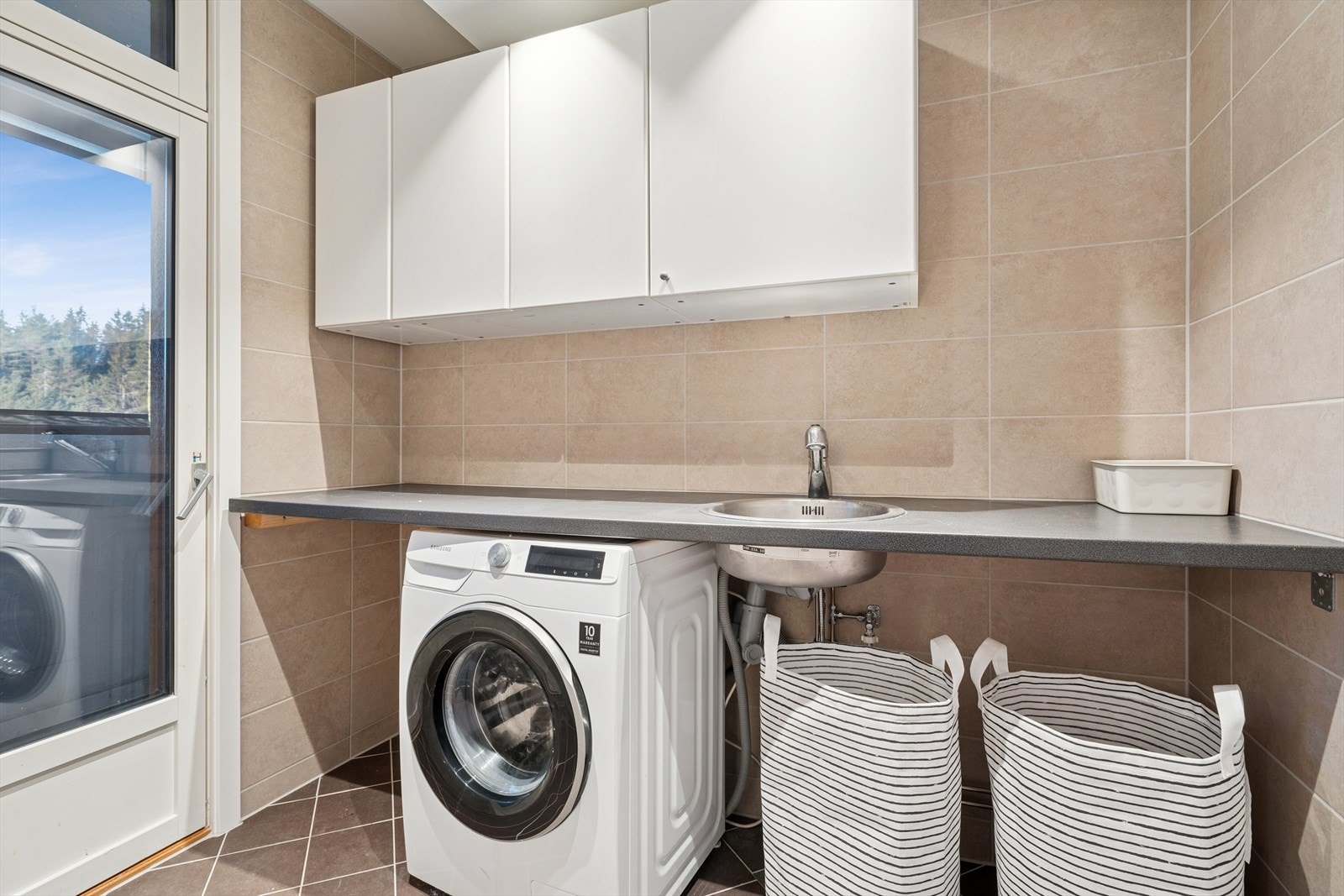 Vaskerommet ble i likhet med baderommet ferdig oppusset i oktober 2025 og er flislagt i samme utførelse. Det er praktisk innredet med en arbeidsbenk som går langs hel vegg, vask, veggskap, og opplegg for vaskemaskin under arbeidsbenken Galleribilde