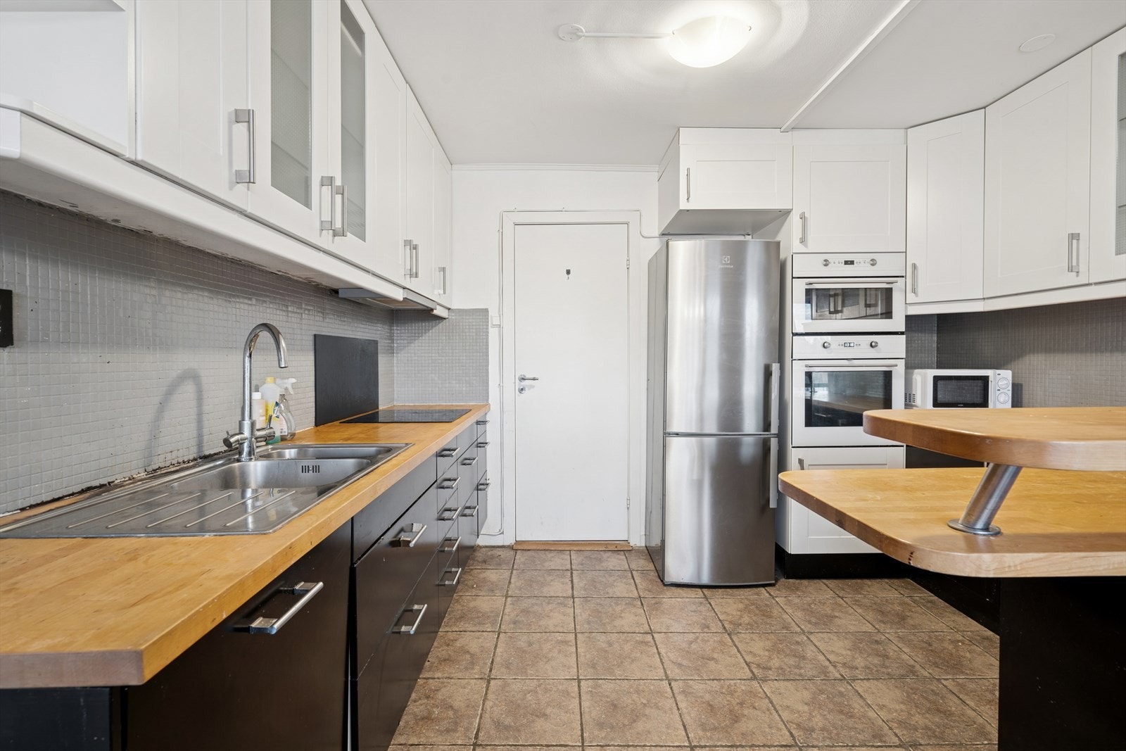 Kjøkkeninnredningen har mørke glatte skapfronter i både over- og underskap, og benkeplate i tre med nedfelt oppvaskkum og avrenningsplate Galleribilde