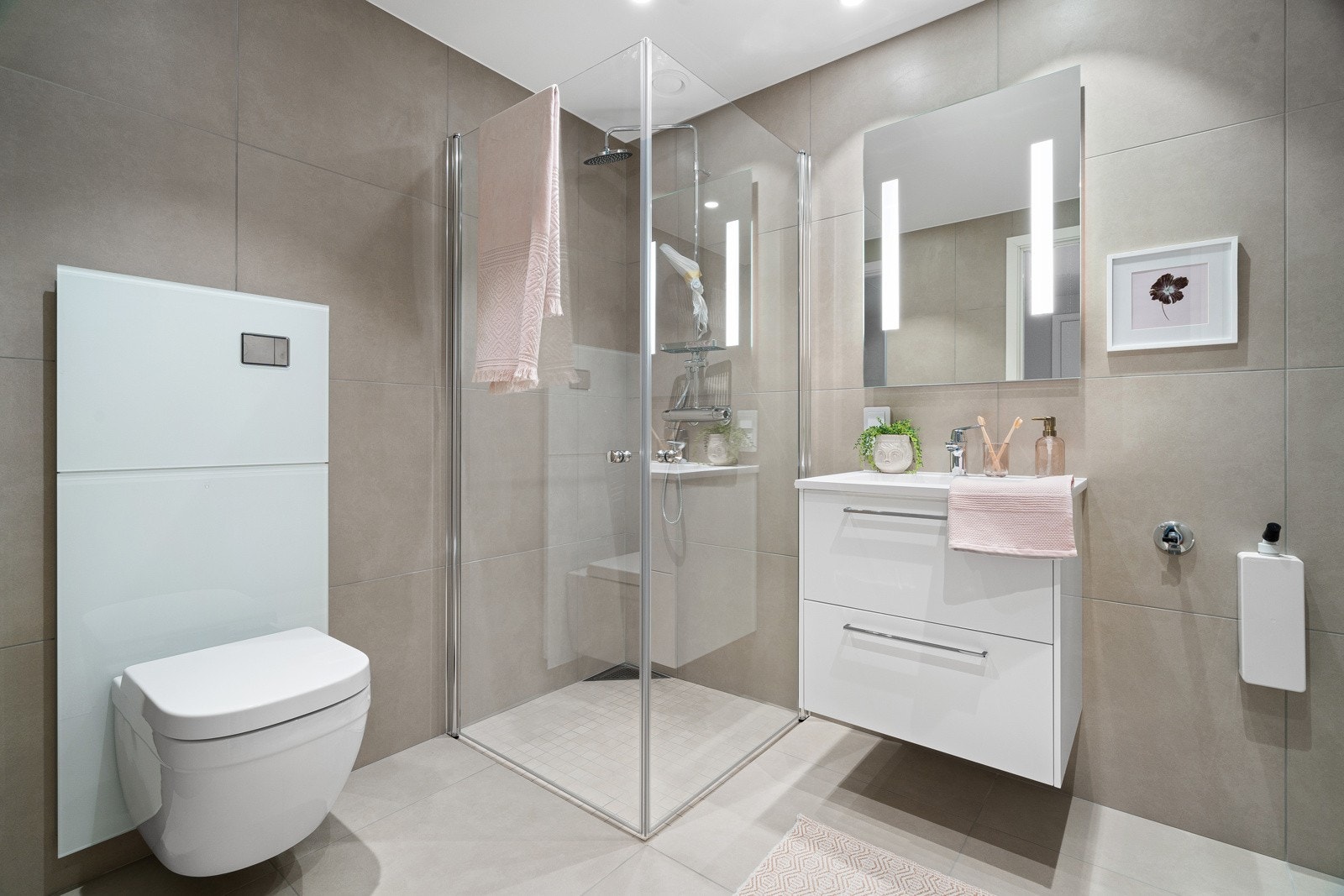 Lekkert flislagt bad med stor dusjhjørne, praktisk vegghengt toalett og god plass for vaskemaskin. Galleribilde