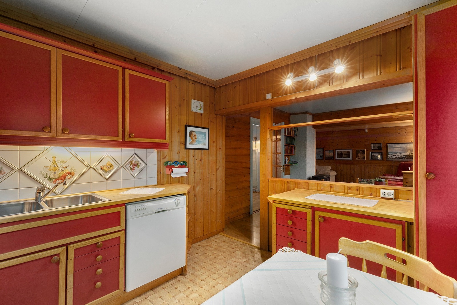 Kjøkken med belegg på gulv, flis på vegg over benkeplate og panel på vegger. Galleribilde