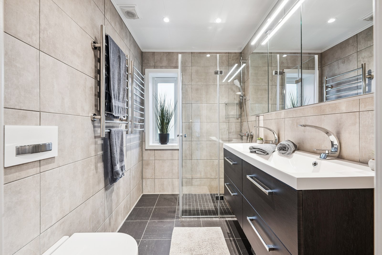 Badet har dusjnisje, vegghengt wc og baderomsinnredning med dobbel vask Galleribilde