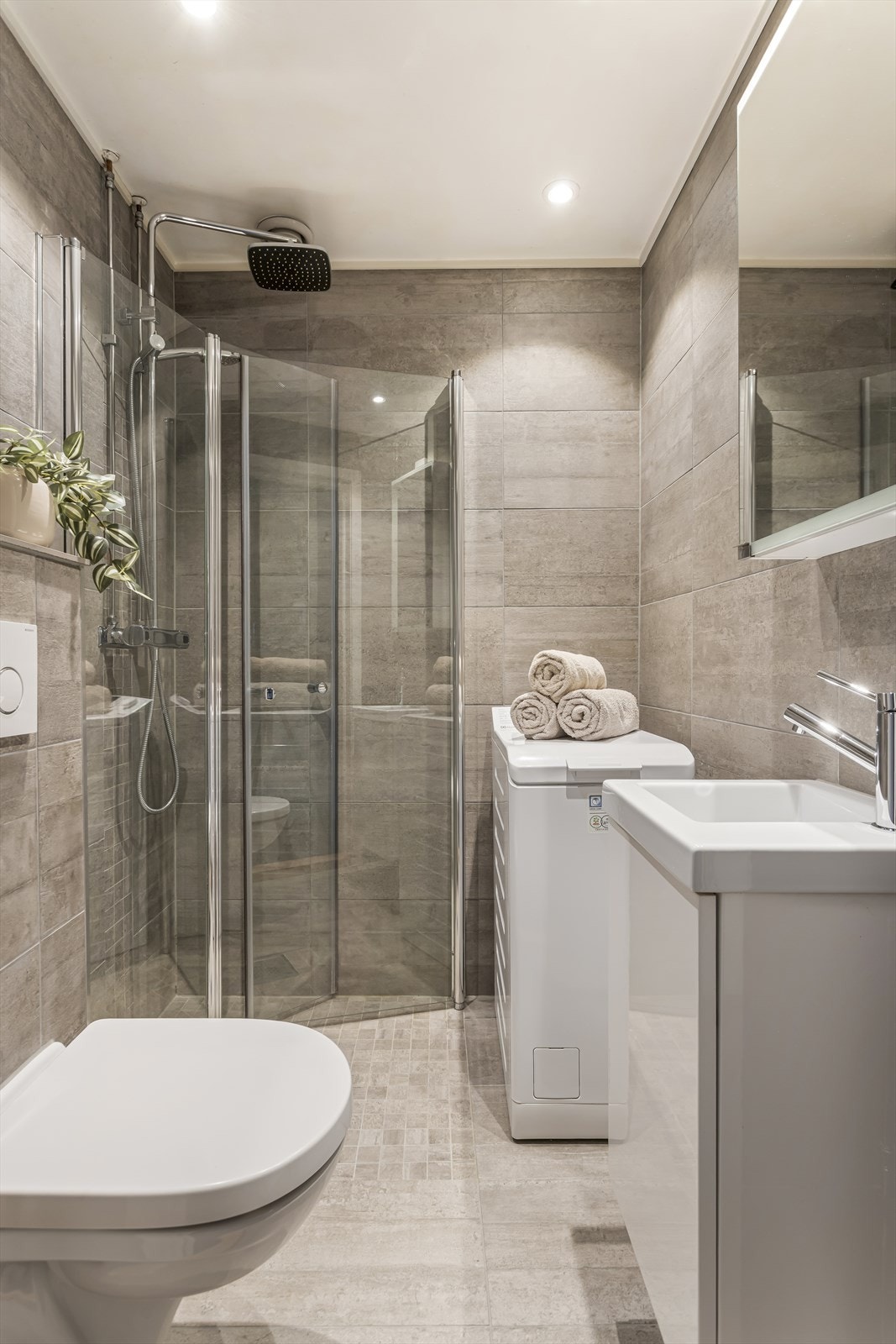 Badet har elektrisk gulvvarme for ekstra komfort, samt heldekkende servant på høyglansfoliert baderomsinnredning og speilskap med integrert lys. Galleribilde