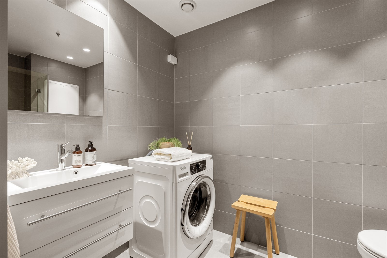 Moderne baderomsinnredning med servant og underskap, samt innfelt belysning i himlingen. Galleribilde