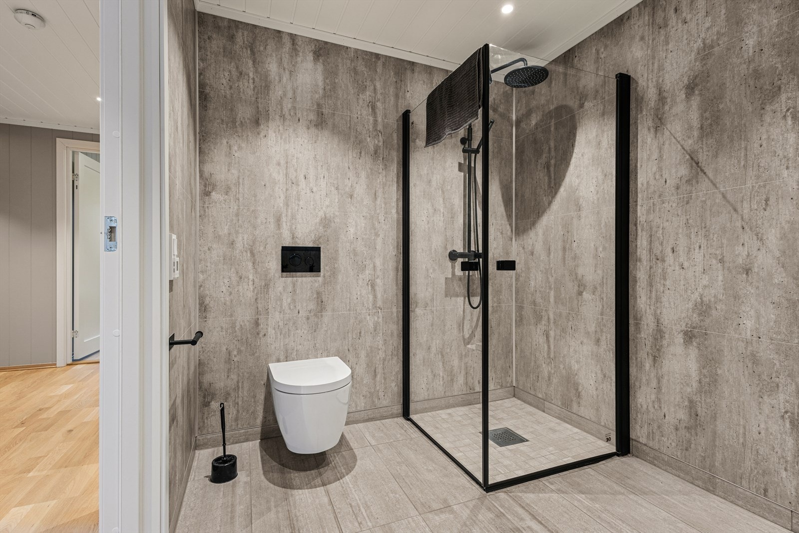 Sort innredning som består av heldekkende servant på skuffeseksjon, speil med lys, vegghengt wc, samt dusjhjørne med rainshower. Galleribilde