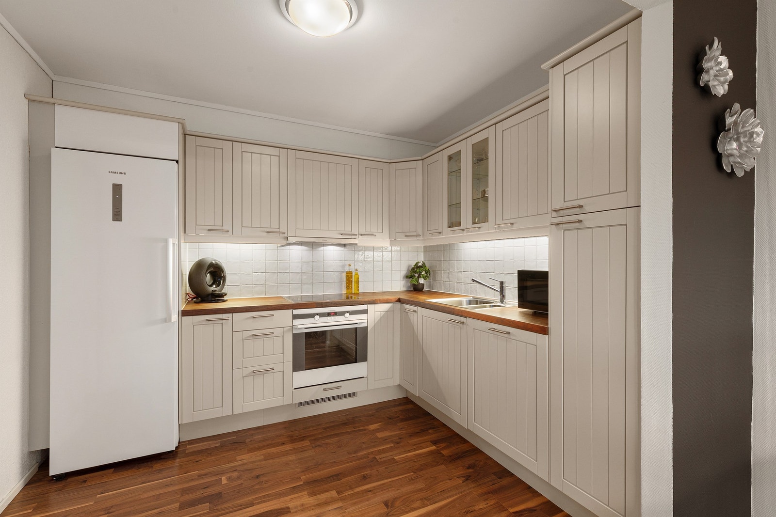 Lyst og fint kjøkken med integrert stekovn, koketopp og oppvaskmaskin Galleribilde