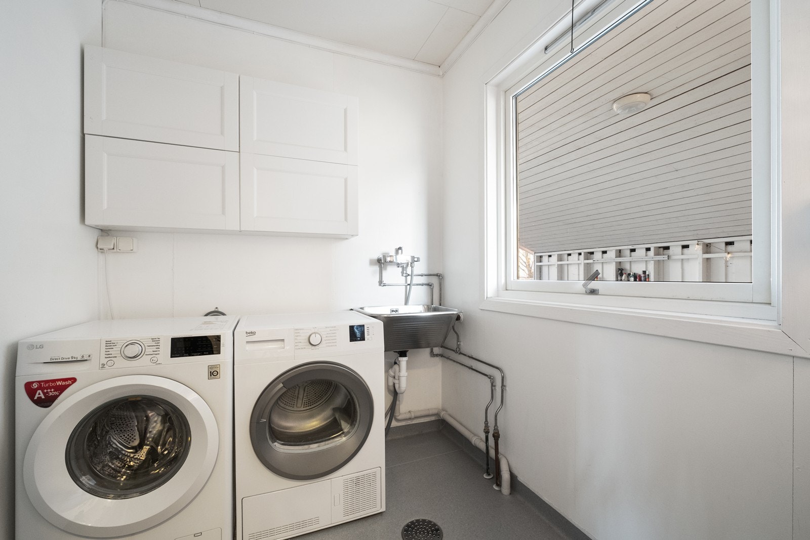 Vaskerommet er innredet med vegghengte skap, utslagsvask og opplegg til både vask og tørk. Galleribilde