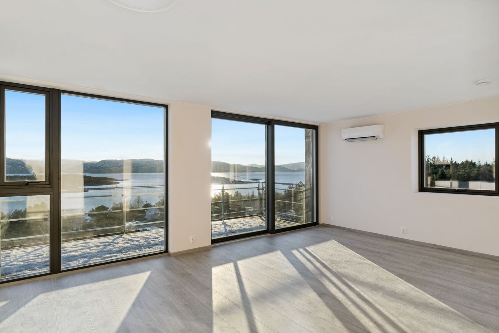 Lys stue med store vindusflater som gir rikelig med lysinnslipp til leiligheten Galleribilde