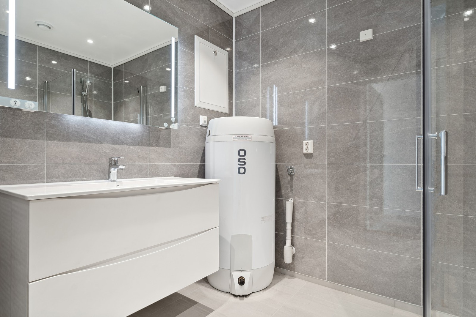 Badet er utstyrt med baderomsinnredning, dusjplass, toalett og opplegg for vaskemaskin Galleribilde