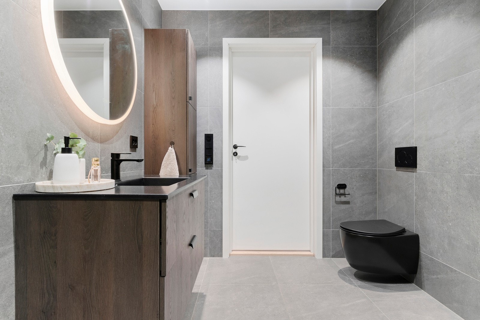 Vegghengt wc, dusjhjørne med innfellbare vegger, servant med innredning, høyskap og sminkespeil, samt egen avdeling for vaskemaskin og tørketrommel i bakkant. Galleribilde