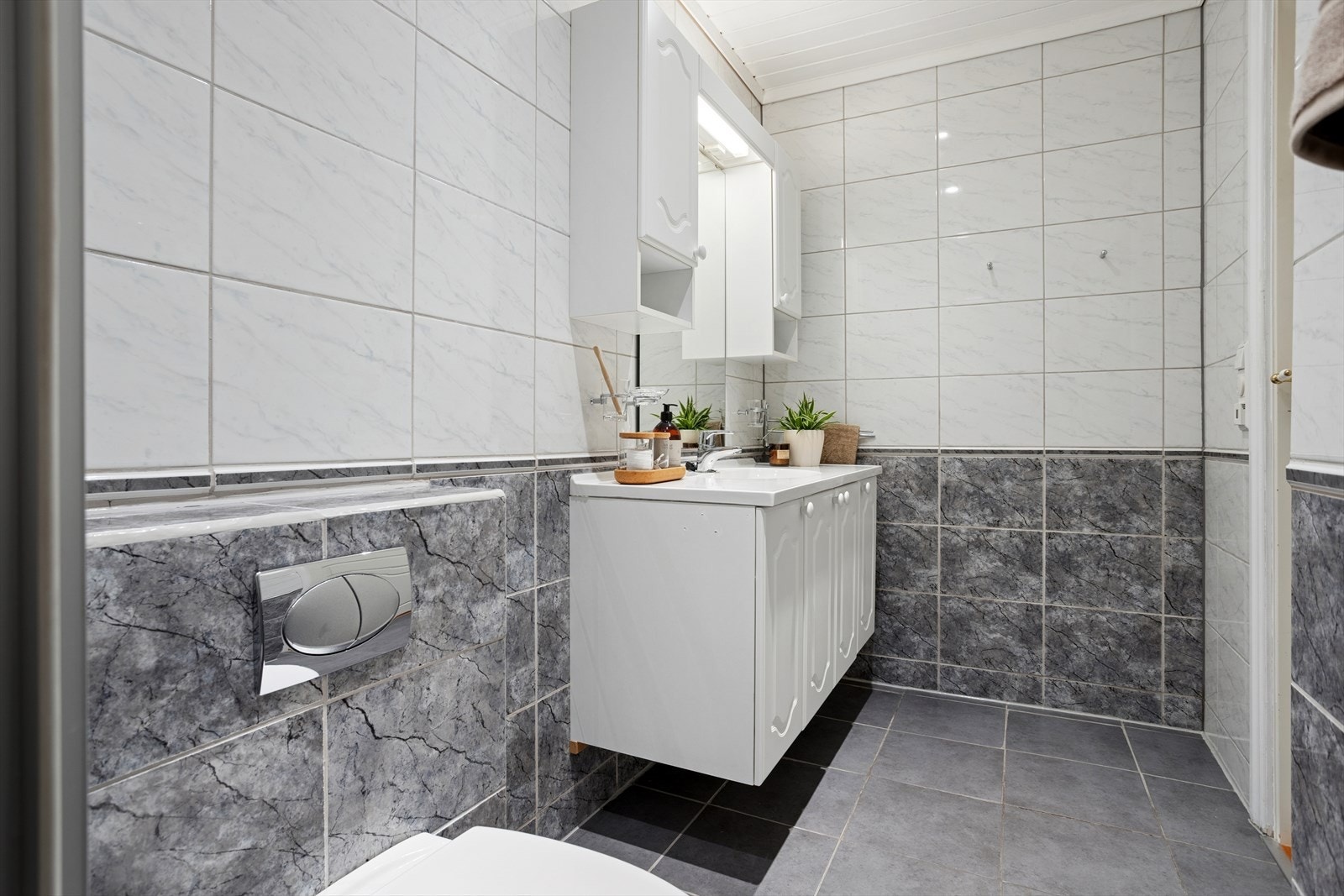 Badet, som er fra byggeåret 2003, fremstår som et rom med god funksjonalitet. Her finner du et benkeskap med nedfelt servant og speil med integrert belysning, som gir et praktisk og ryddig preg. Galleribilde