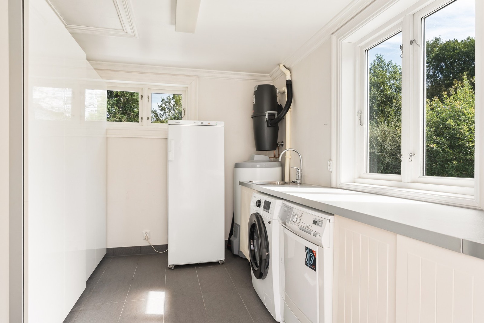 Vaskerom på ca. 8 kvm med varmekabler i gulv, god plass til vaskemaskin, tørketrommel og innredning, egen utgang, samt sentralstøvsuger og 180 liters varmtvannstank. Galleribilde