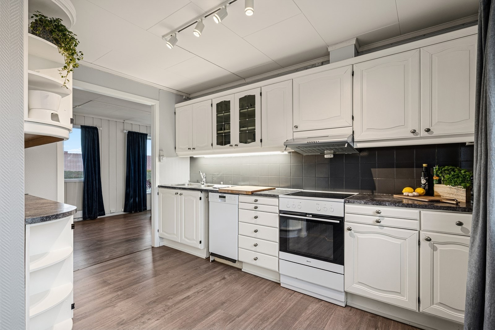 Kjøkkenet har profilerte fronter, fliser mellom over- og underskap og foliert benkeplate. Galleribilde