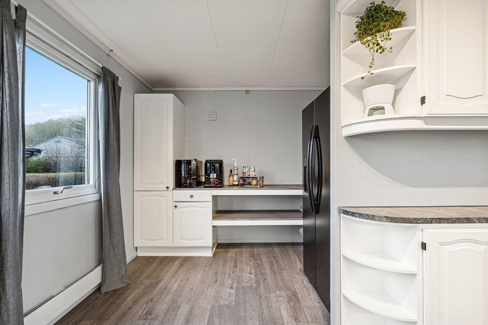 En praktisk ekstra kjøkkensone som fungerer utmerket som grovkjøkken eller arbeidsrom, med rikelig benkeplass og oppbevaring. Galleribilde