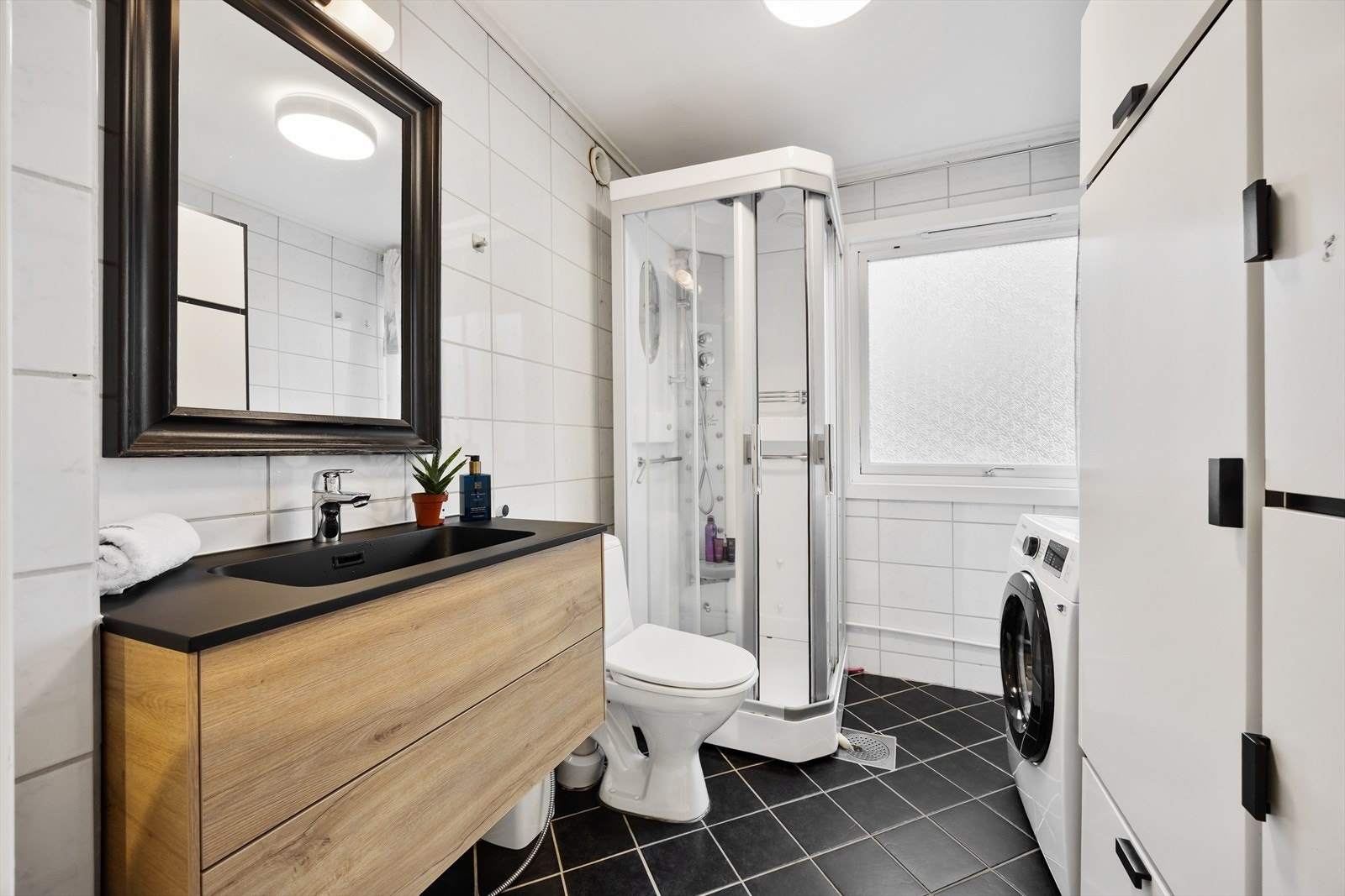 Badet er flislagt og utstyrt med dusjkabinett og en nyere servantinnredning. Galleribilde