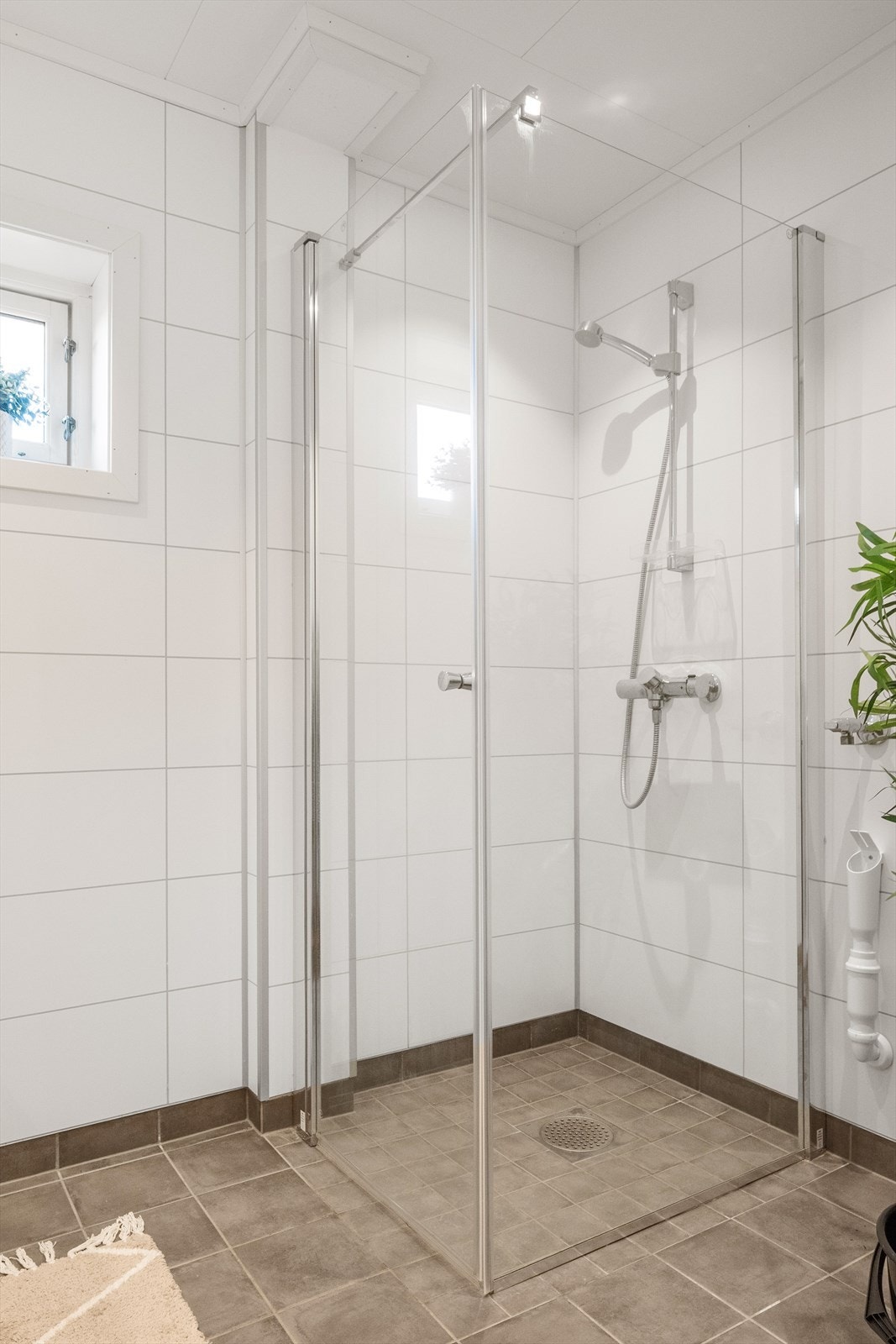 Innredet med servantskap med servant, opplegg for vaskemaskin og vegghengt dusj med skjermdører i herdet glass. Galleribilde