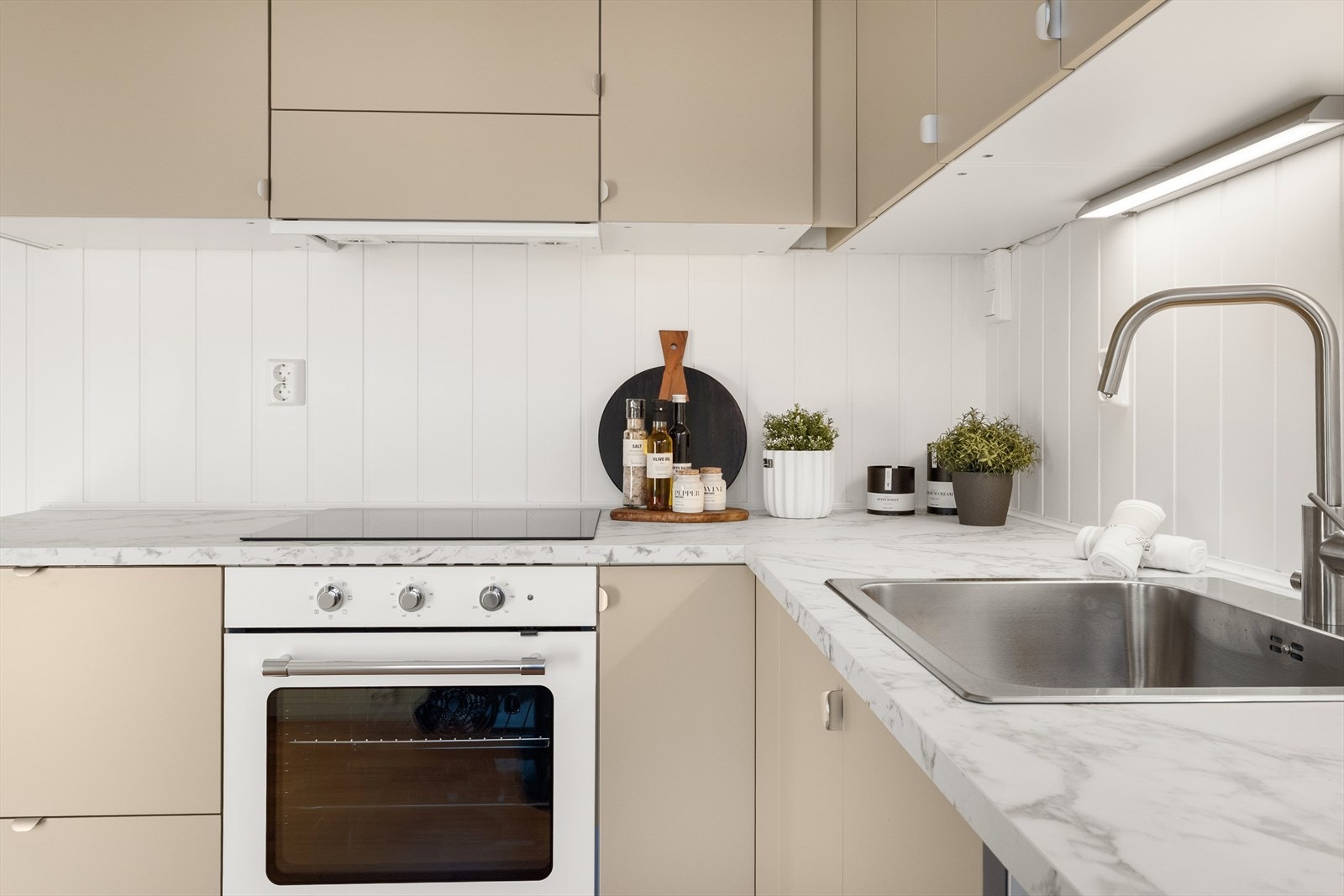 Kjøkkenet har integrert induksjonstopp og stekeovn, samt plass til frittstående oppvaskmaskin og kjøl-/fryseskap. Galleribilde