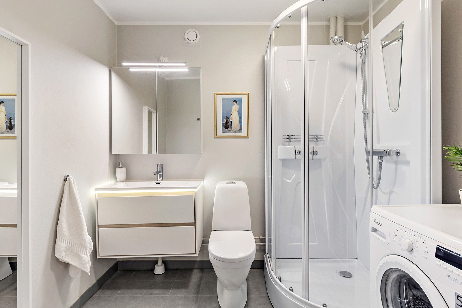 Romslig bad med dusjkabinett, servant i innredning og speilskap med oppbevaring Galleribilde