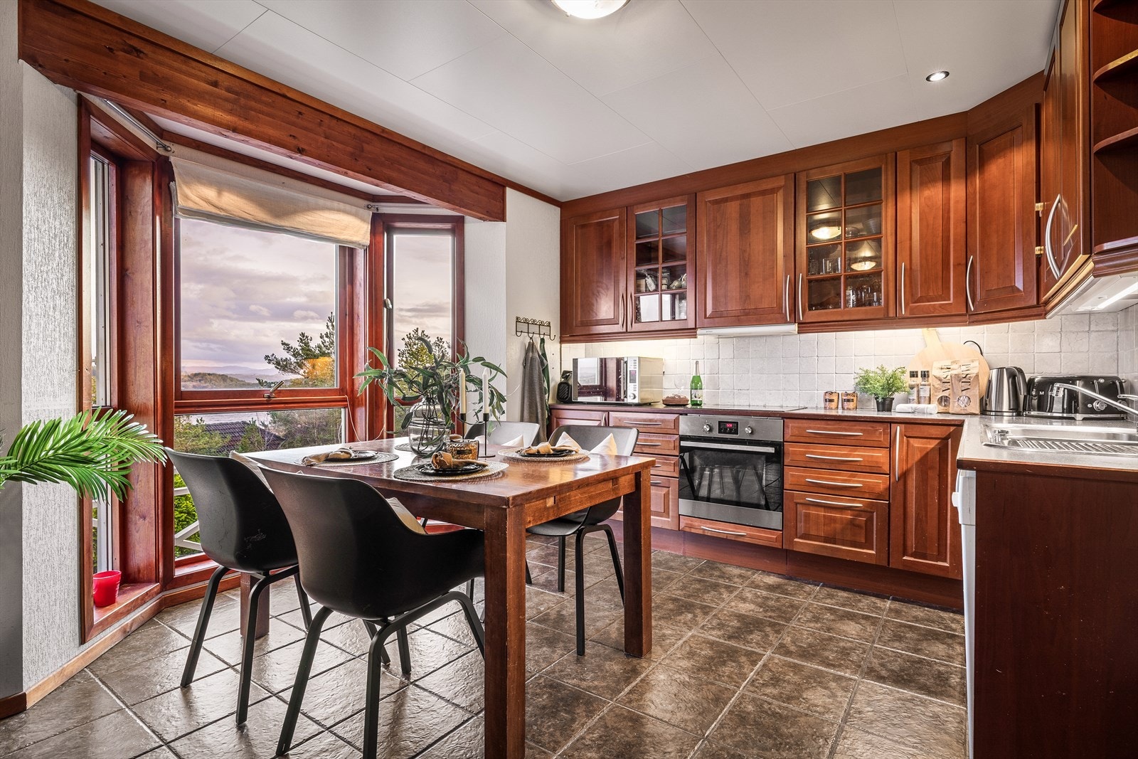 Kjøkkenet i 2. etasje er romslig og innbydende, med profilerte fronter, to overskap med glass, laminert benkeplate og fliser over benk. Galleribilde