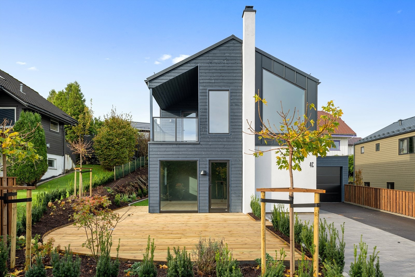 Pent opparbeidet tomt med steinheller og asfalt i gårdsrommet, samt solrike terrasseplattformer både foran og bak boligen. Galleribilde