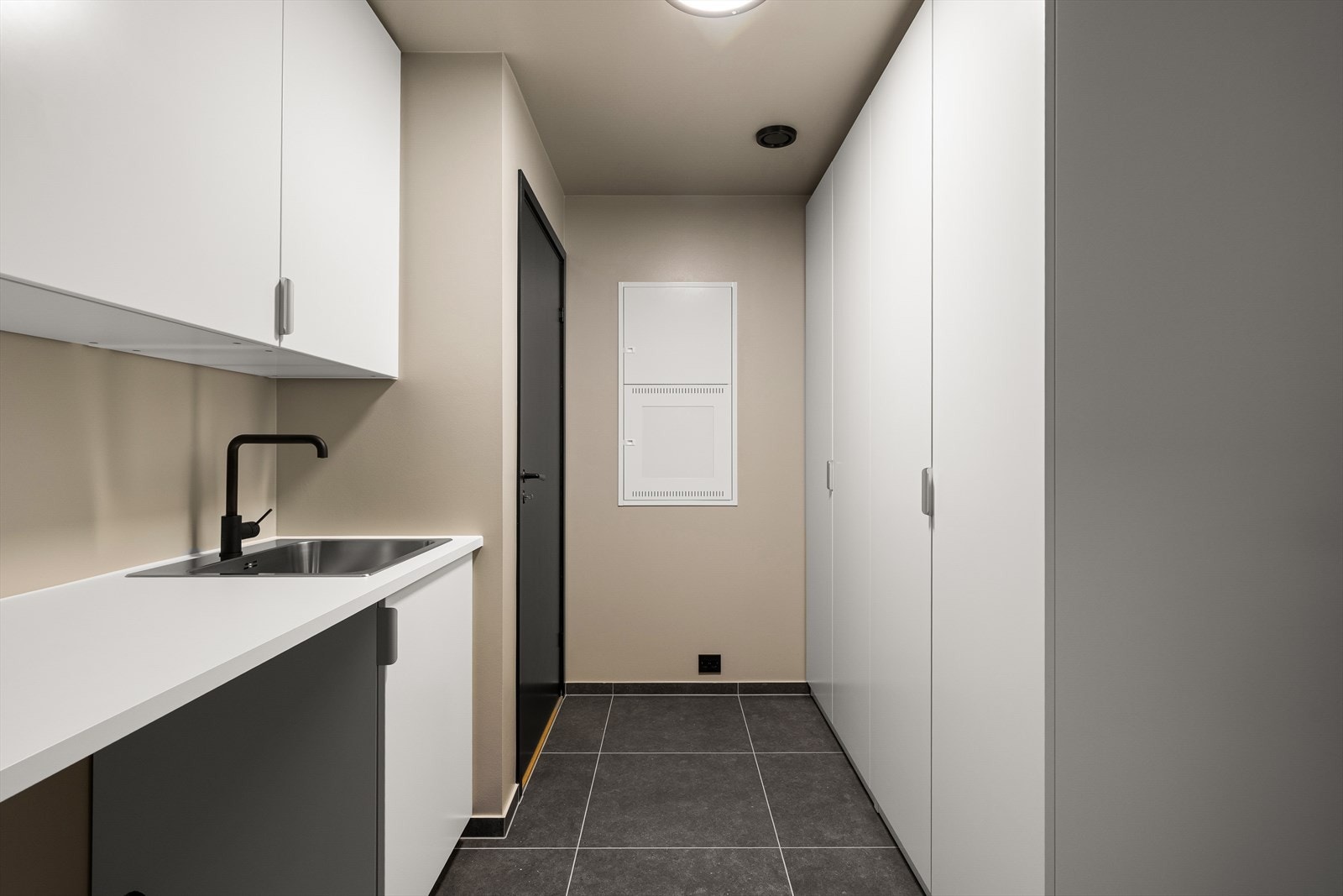 Praktisk med egen biinngang med fliser på gulv og innredning med skap og benkeplate. Det er innredet med stort garderobeskap og utslagsvask. Opplegg for vaskemaskin. Galleribilde