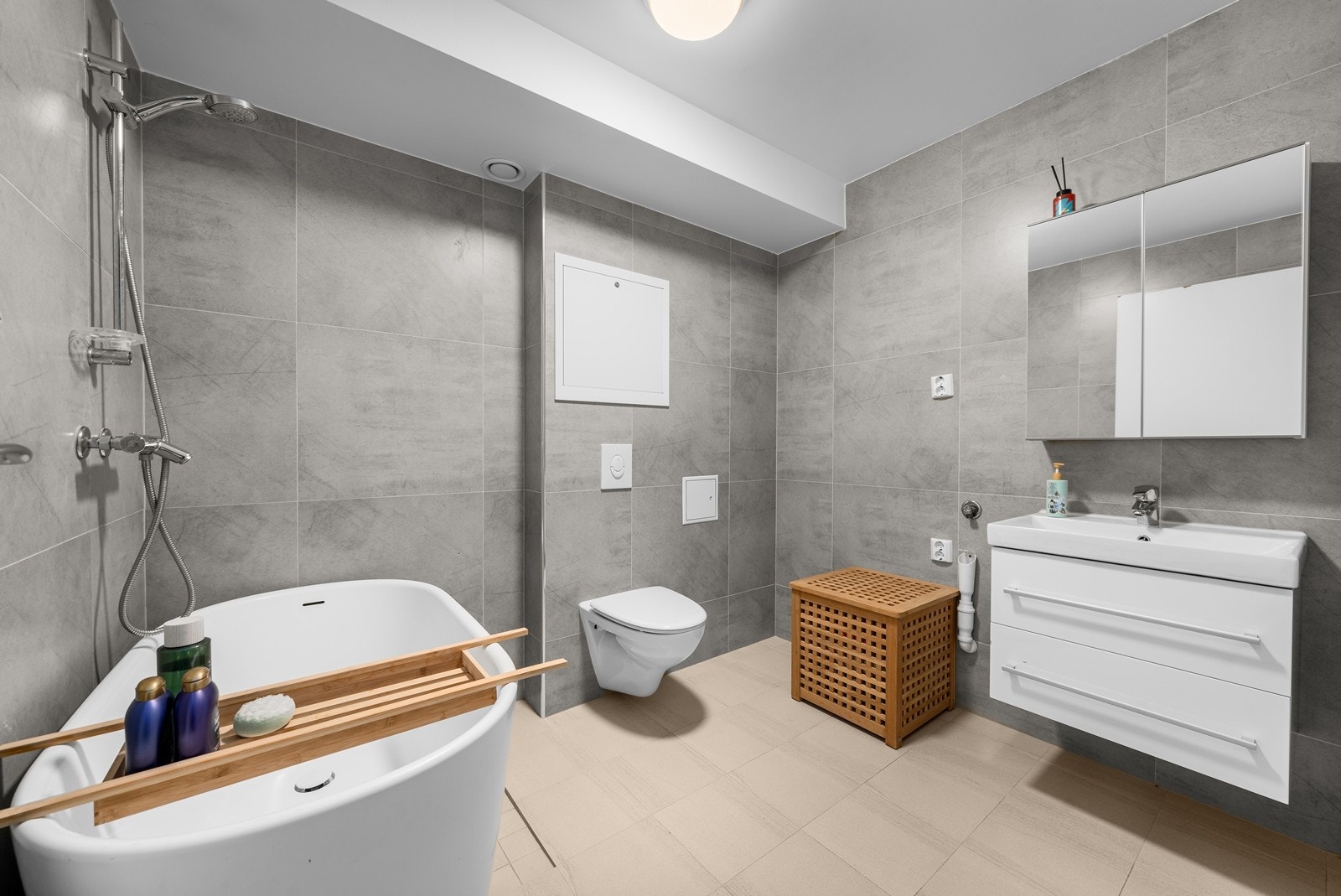 Badet fremstår moderne og innbydende, med flislagt gulv med elektrisk gulvvarme og flislagte vegger som gir et helhetlig og tidløst uttrykk. Himlingen er malt i en lys tone. Vegghengt servantskap med heldekkende servant. Speilskap med overlys. Galleribilde