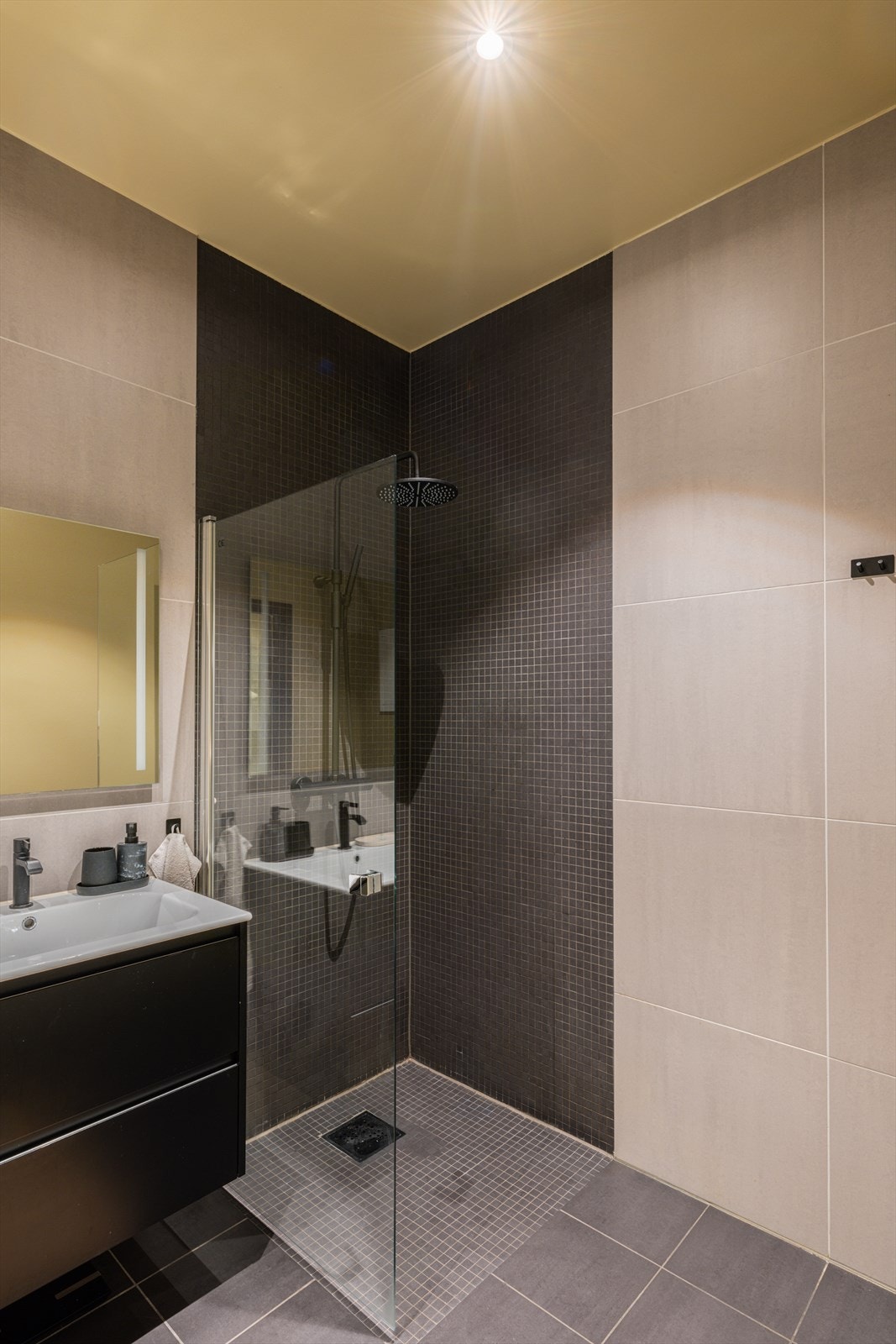 Badet er innredet med veggmontert WC, dusjplass, servant med ettgreps blandebatteri i innredning samt opplegg for vaskemaskin. Galleribilde