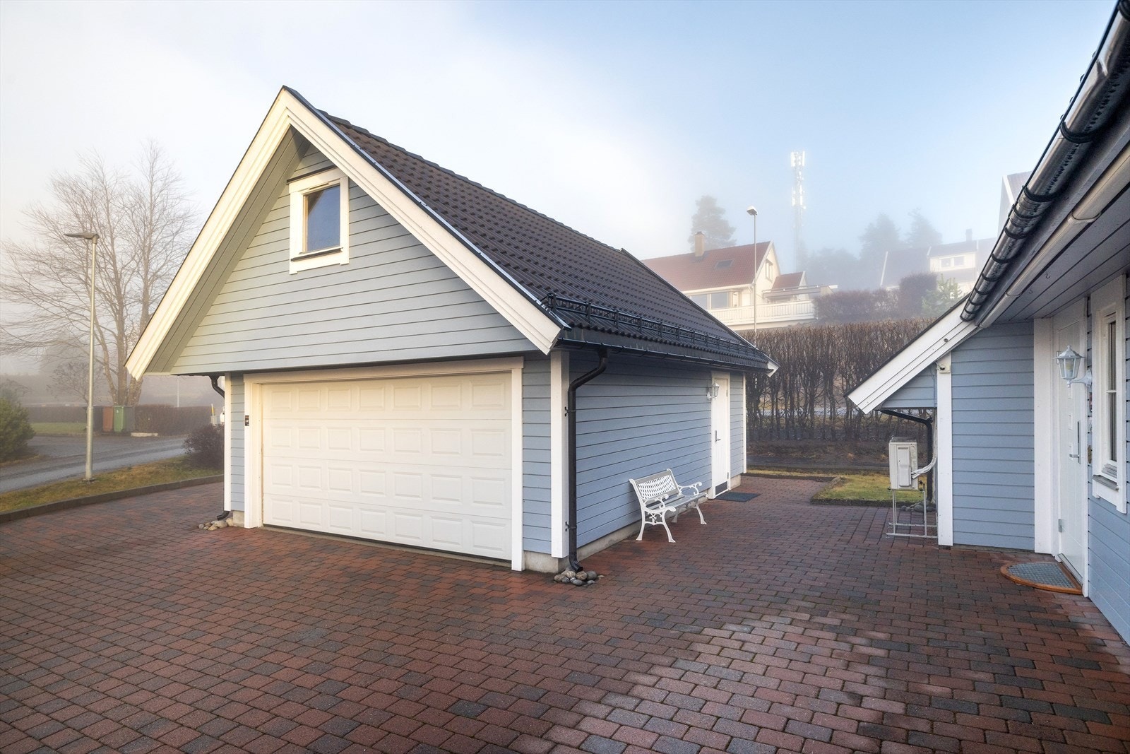 Den frittstående dobbelgarasjen har elektrisk port og godt med lagringsplass på loft Galleribilde