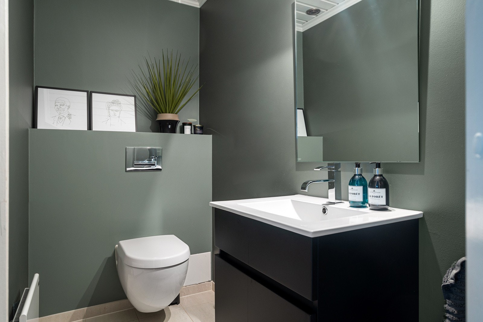 Toalettrommet i 1. etasje ligger i praktisk tilknytning til entréen og oppholdsrommene. Rommet fremstår moderne og delikat, med vegghengt toalett, servant med underskap og et stort speil. Galleribilde