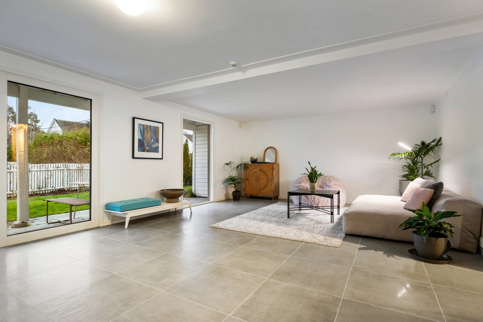 Store fliser, lyse overflater og direkte utgang til hagen gjør rommet svært anvendelig og skaper et naturlig tilleggsoppholdsrom for hele familien. Galleribilde