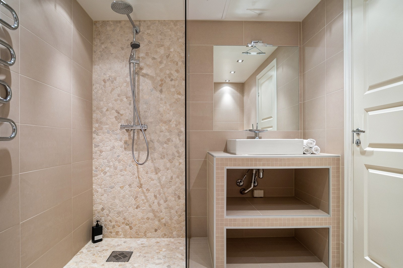 Badet i underetasjen fremstår som et delikat og innbydende rom med moderne materialvalg. Rommet er utstyrt med både dusj og badekar. Dusjsonen er adskilt med glassvegg og har flotte mosaikkfliser som gir et eksklusivt uttrykk. Galleribilde